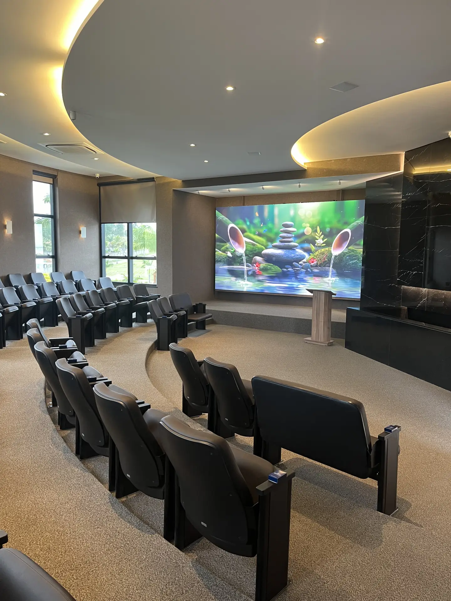 Sala de cerimônias do Memorial Park com poltronas em semicírculo e telão